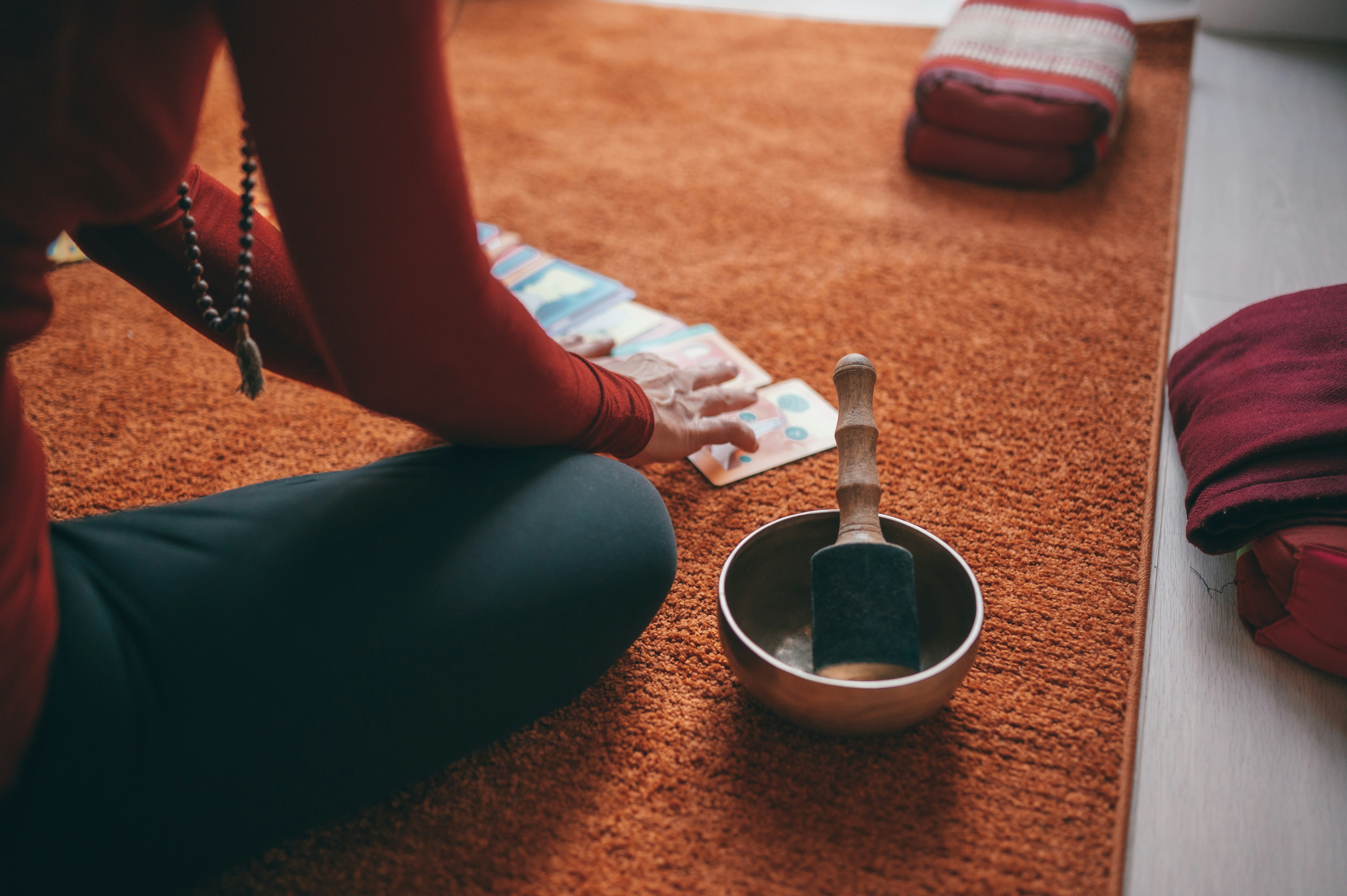 person in teal pants sitting on floor with black round ceramic bowl